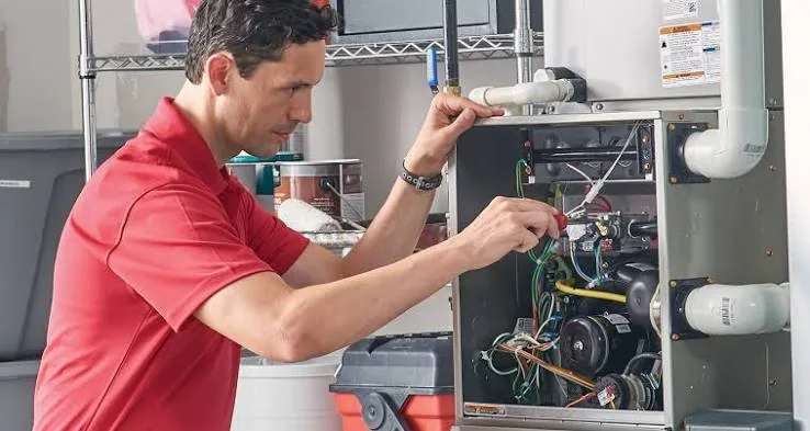 Technician inspecting a residential furnace and indoor HVAC system