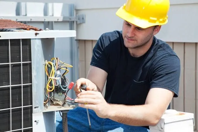 Technician repairing the electrical connections inside an outdoor air conditioner
