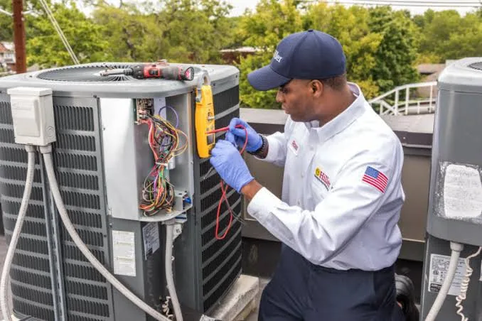 Technician testing a rooftop air conditioning unit with diagnostic tools