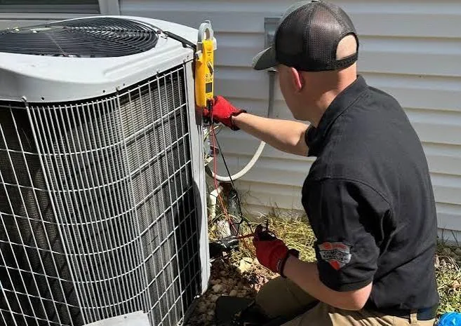 Technician measuring electrical current on an outdoor air conditioning condenser