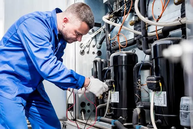 Technician working on HVAC compressors and refrigerant piping