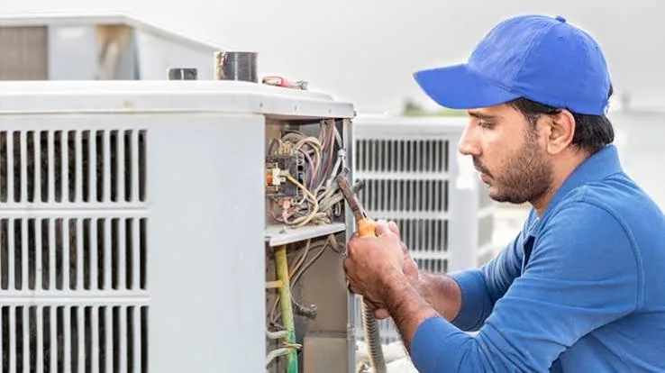 Technician servicing the electrical panel of a commercial air conditioning unit