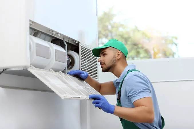 Technician inspecting a wall-mounted indoor air conditioning filter